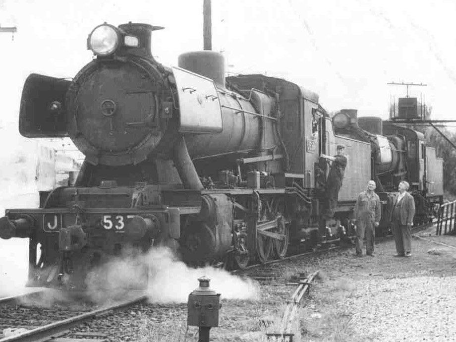 Historic photo of stopped steam traing with driver and two other men next to it