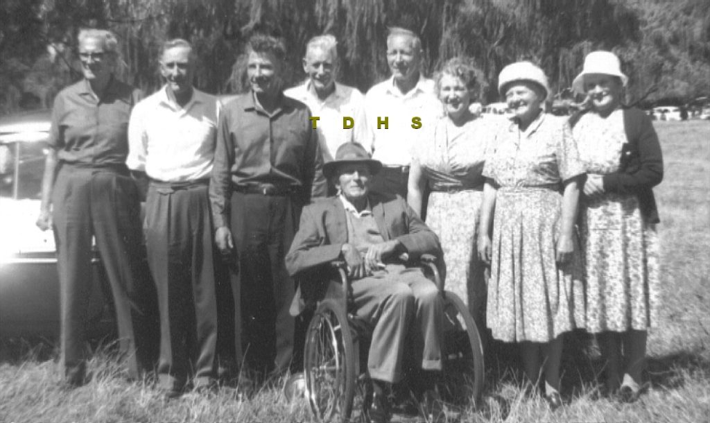 Historic photo of family group in a park, with older man in wheelchair