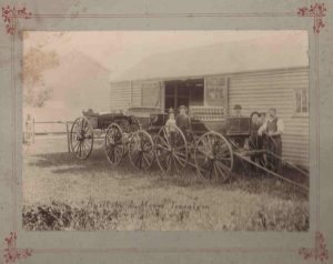 Historic photo of men and children proudly standing with horse and cart wagons they had made