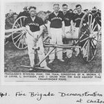 Newspaper clipping showing four men with fire hydrant, hose and reel on large wagon