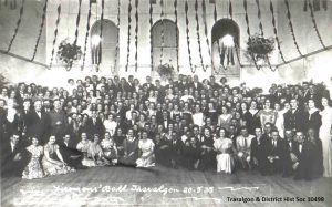 Historic photo of people approx 200 people gathered together, with streamers decorating the ceiling, at the Firemans Ball in Traralgon 1935