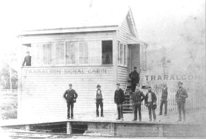 Historic photo of the wooden signal cabin and nine men standing. Men look like a couple of conductors and others could be railway workers