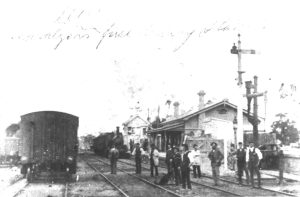 Historic photo of the Traralgon Railway station showing carriages, men standing around and railway buildings