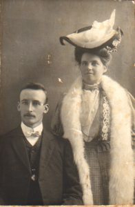 Historic photo of man and his wife, with man wearing suit and woman in fur shawl and large hat 1906