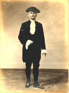 Historic photo of Rev Steele wearing coat and tail suit, frilly collar and cuffs and brim hat in 1908