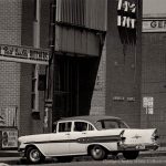 Black and white photo of 1950s car parked in street