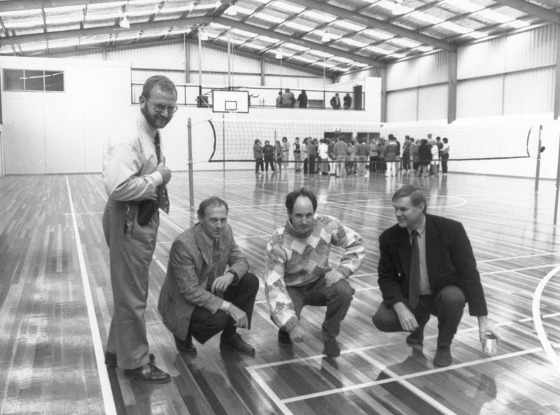 An original black and white photographic print of the interior of the new Basketball Stadium at the Traralgon Secondary College. In the foreground from left, Ray van Poppel, Ron Elloitt, Terry Batt and Peter Duff.