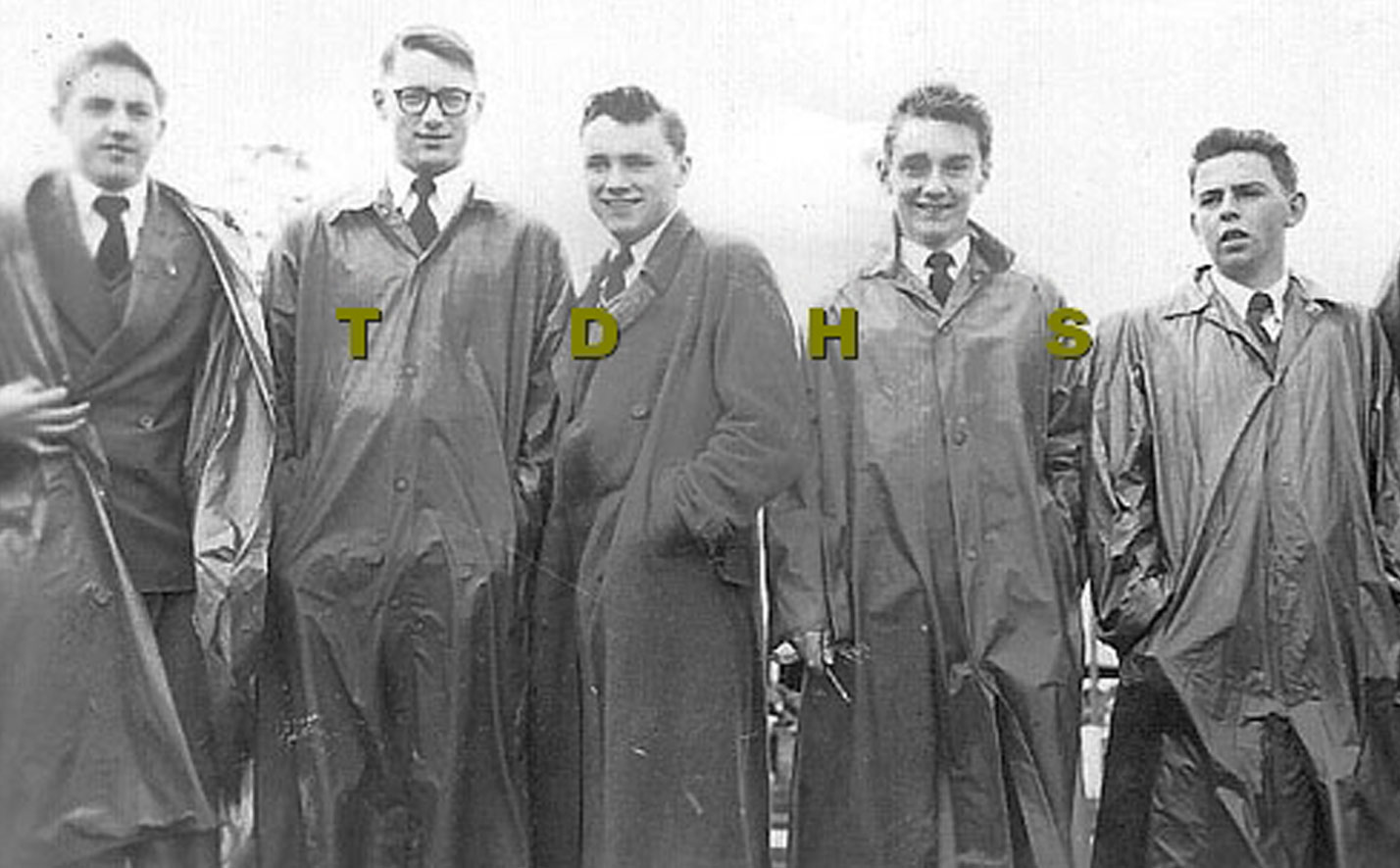 Blakc and white photo of five teenage school boys wearing uniforms and long coats